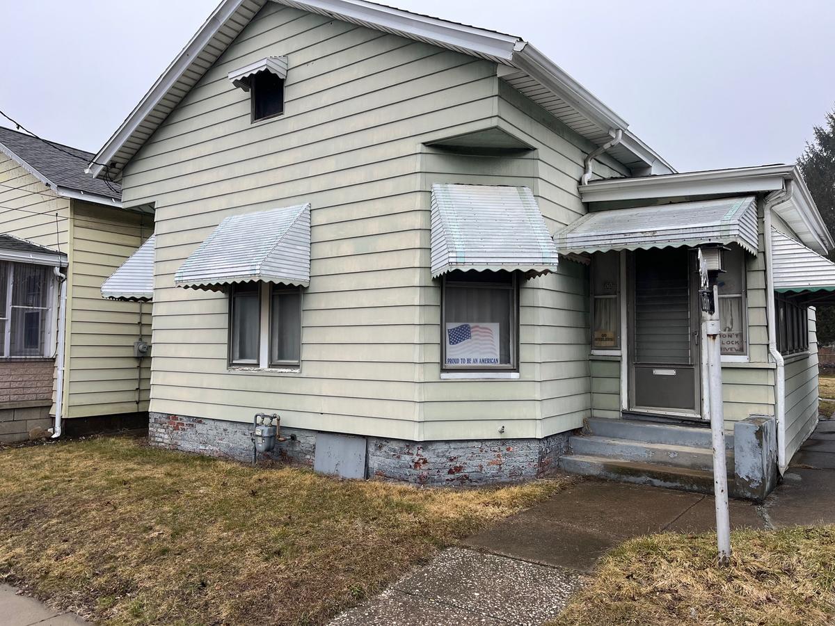 Erie NY 1920s bungalow — green siding, storm awnings, vacant