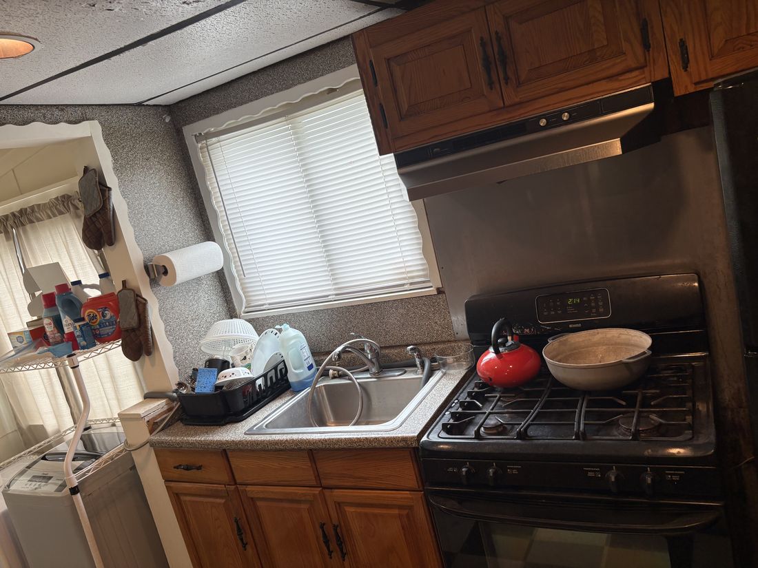 Original kitchen run with dated cabinetry, gas range and sink in the Hempstead, NY home