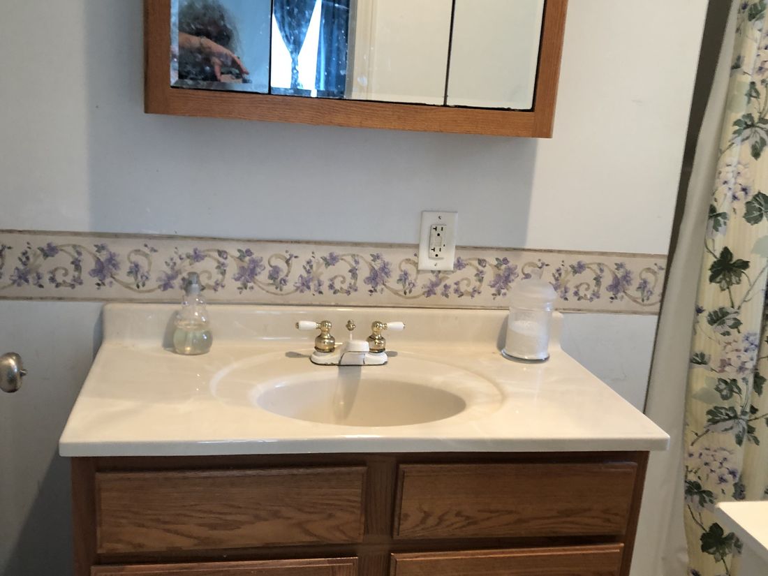 Main bathroom with original oak vanity and dated fittings in Holland Patent, New York