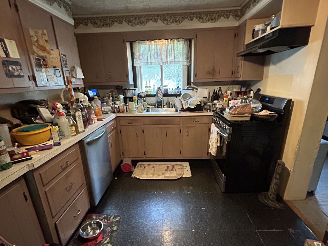 Original kitchen with dated wood cabinetry in the West Babylon, NY ranch, photographed as purchased