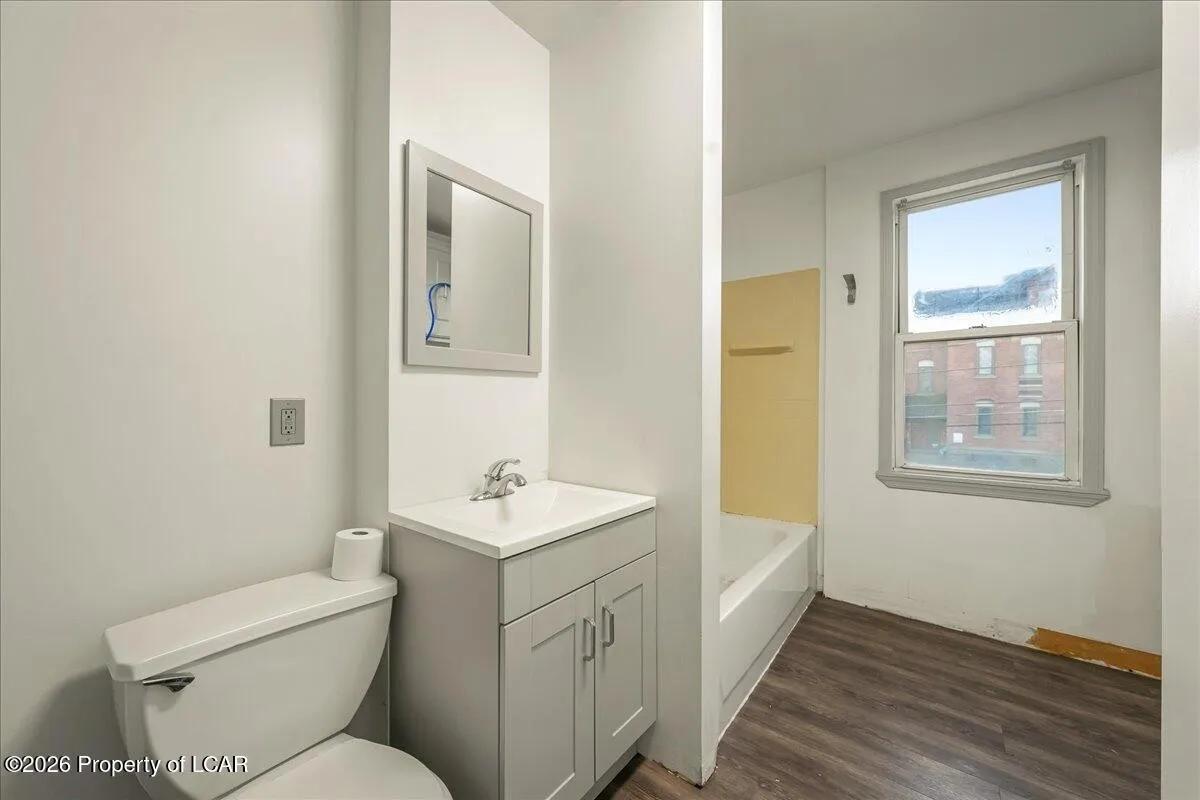 White Plains unit bathroom after — new vanity, toilet, and LVP flooring installed