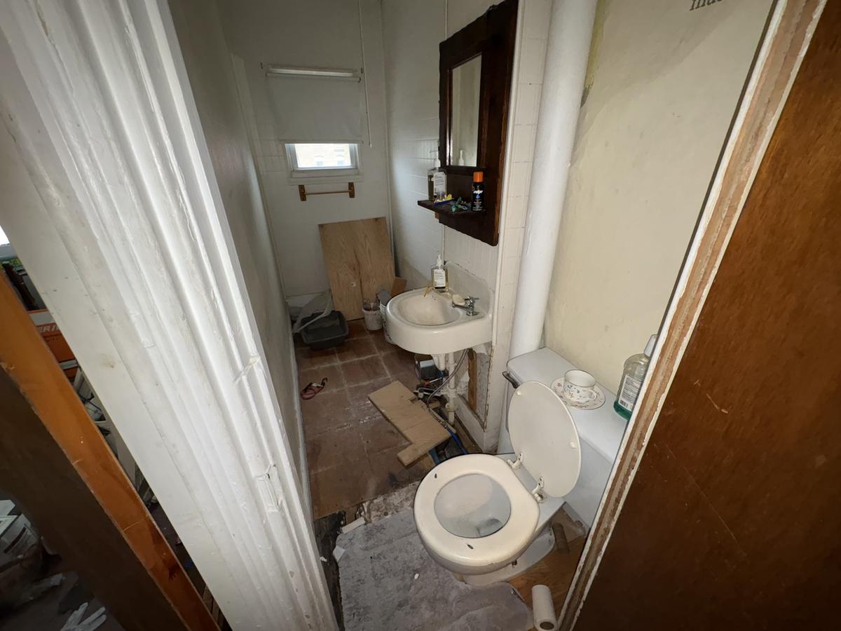 White Plains unit bathroom before — original fixtures, debris, disrepair