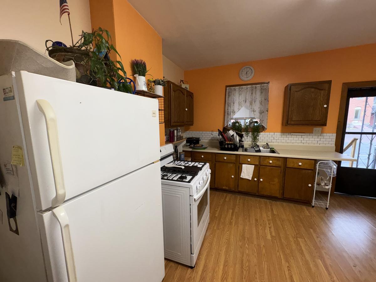 White Plains unit kitchen before — orange walls, wood cabinets, occupied