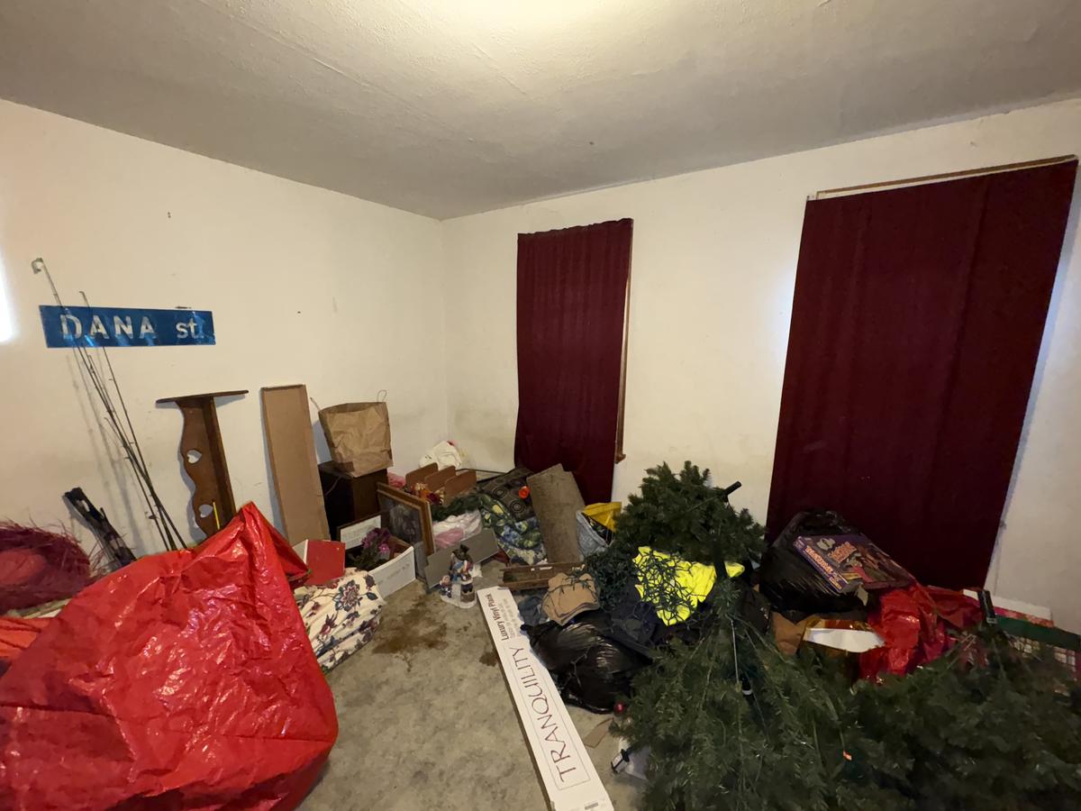 White Plains unit room before — cluttered, red curtains, abandoned belongings