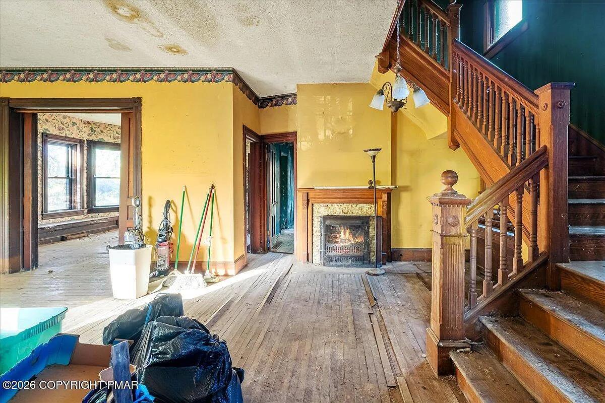 Victorian entry hall after — original carved oak staircase, marble fireplace, hardwood floors