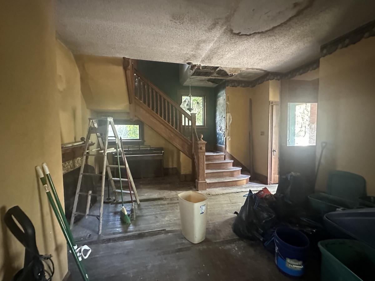 Victorian entry hall before — original carved staircase, collapsed ceiling, water damage