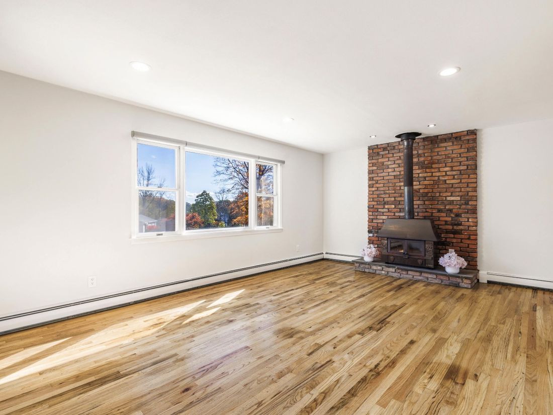 Living room with refinished hardwood floors and the original brick wood stove hearth retained
